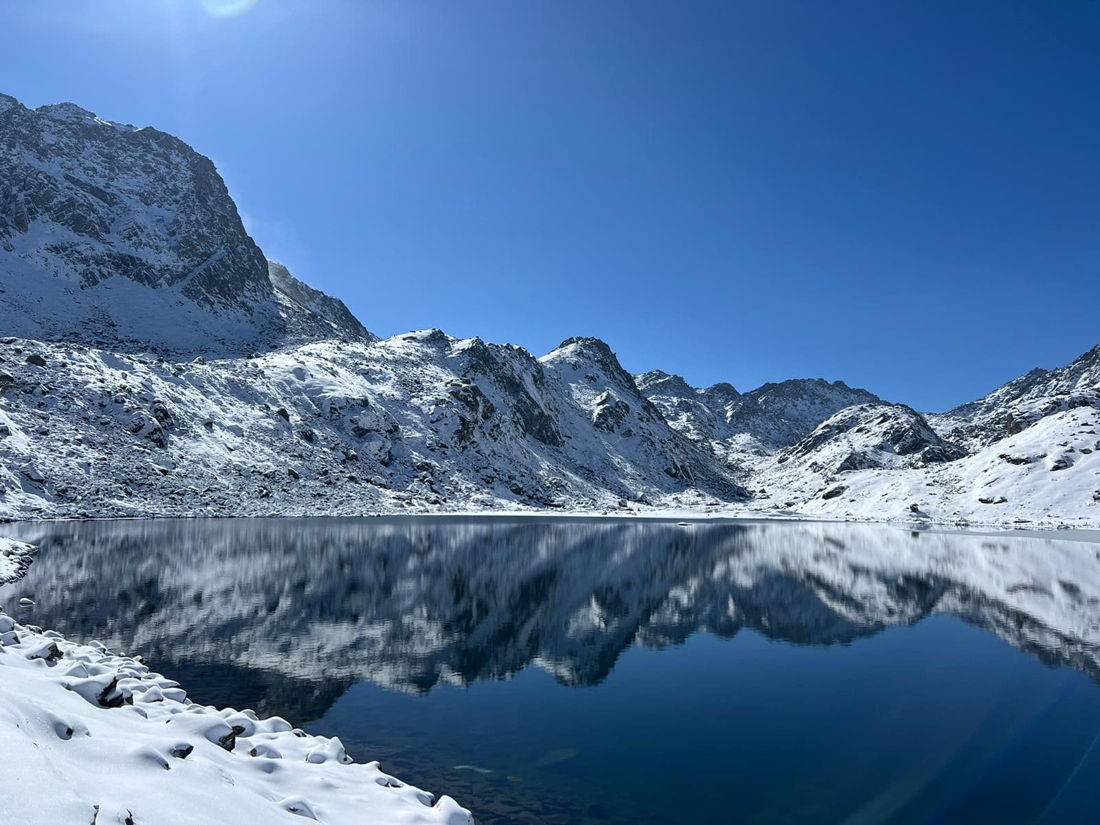 Snow-covered peaks reflected in a still high-altitude lake