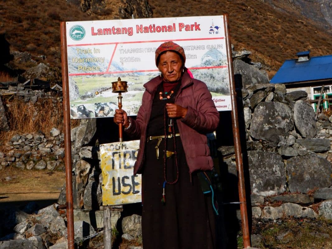 Local woman with prayer wheel at a Langtang National Park sign