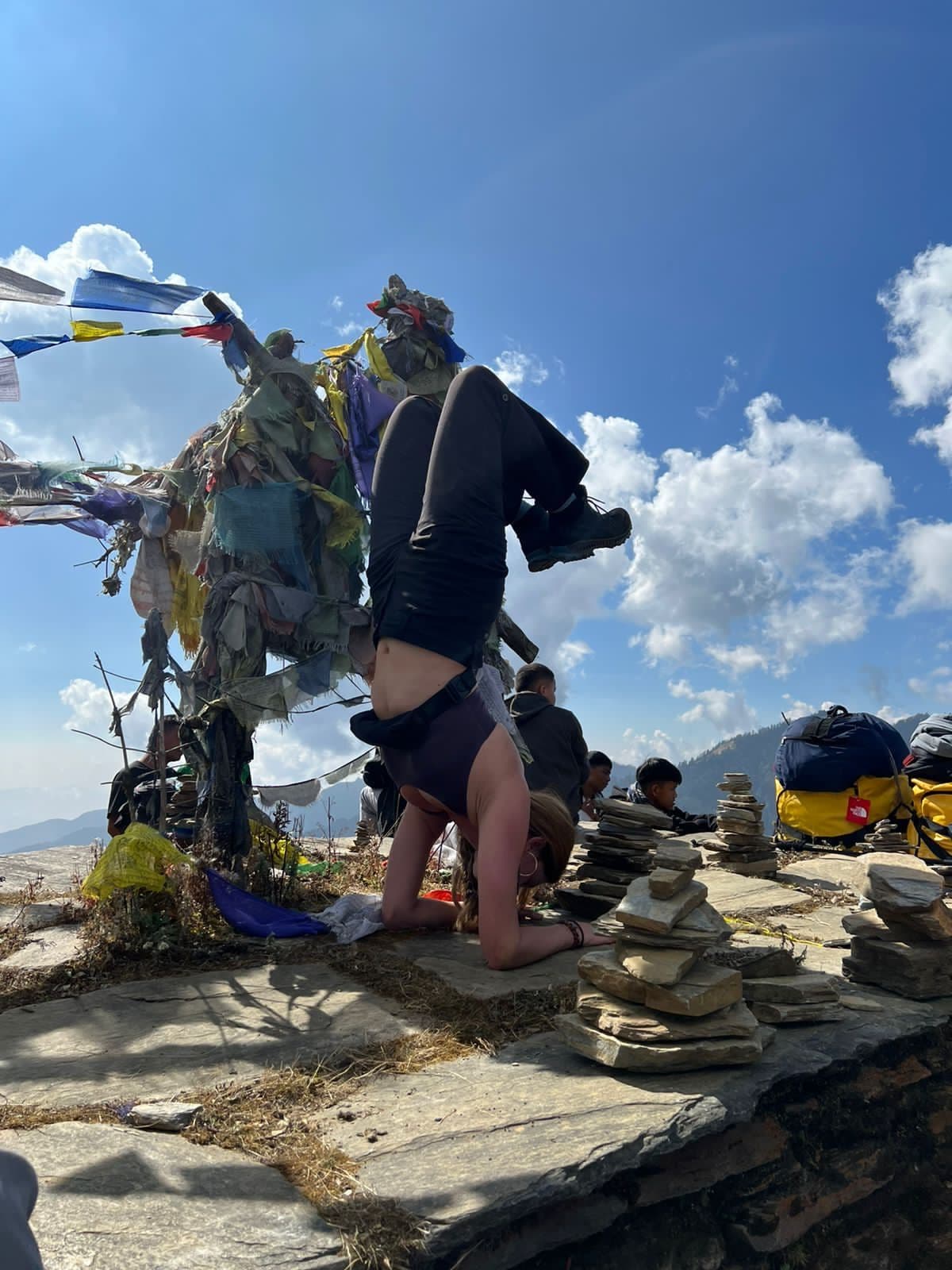 Trekker standing by prayer flags on a summit cairn