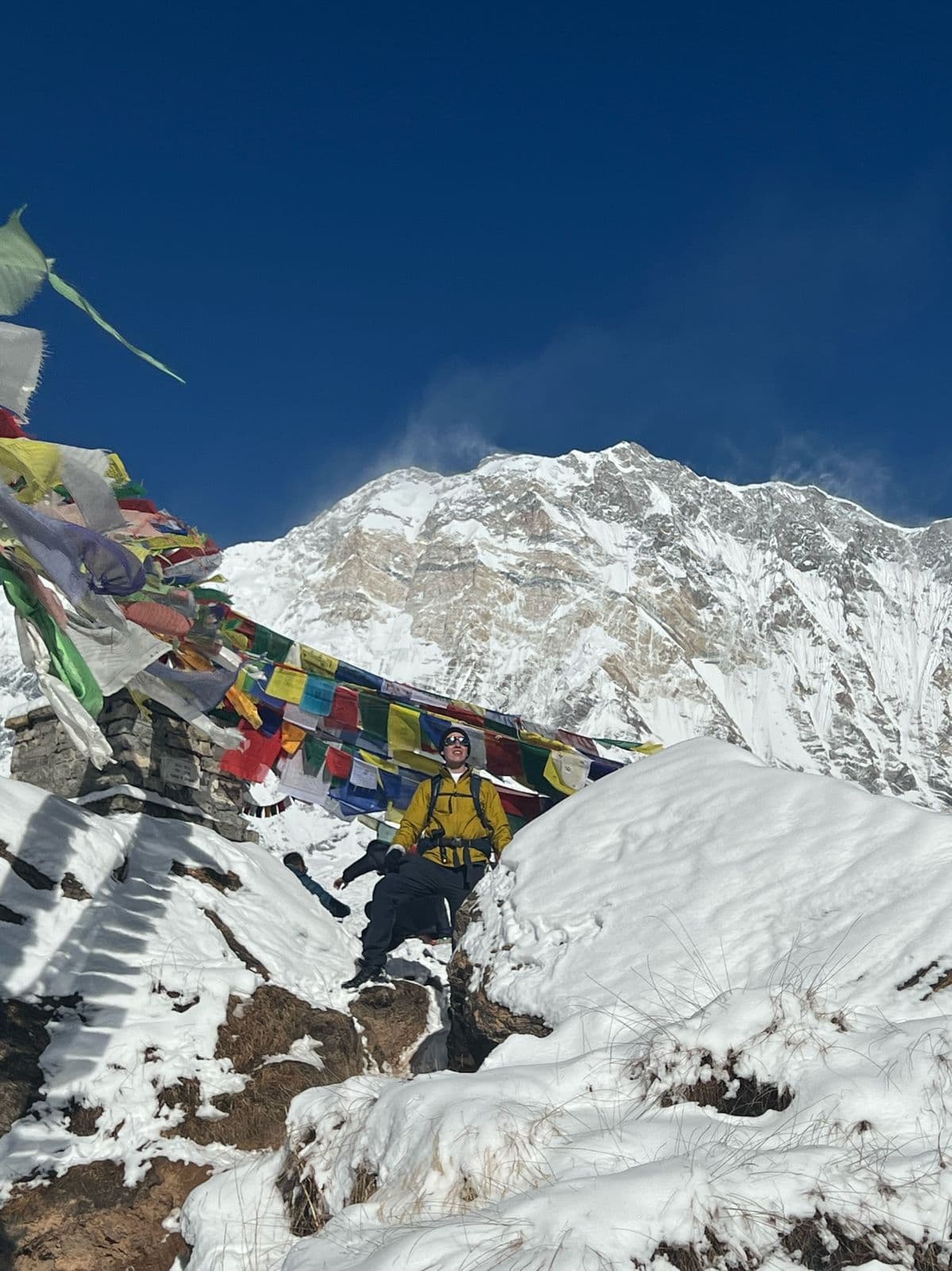 Prayer flags on a snowy ridge below a Himalayan peak