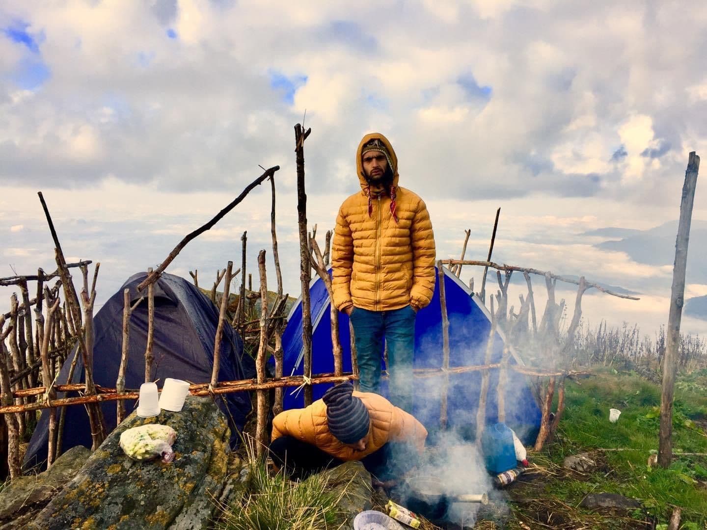 Trekker beside a smoky campfire at a wild camp