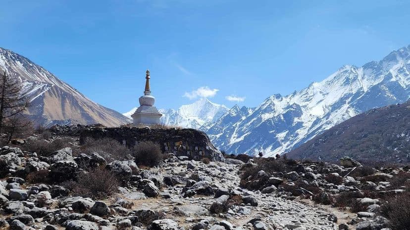 White stupa on a rocky ridge with snowy mountains