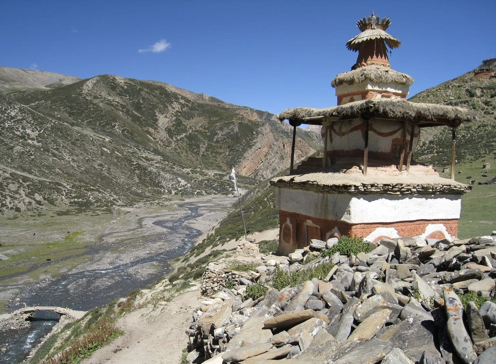 Old chorten above a wide glacial river valley