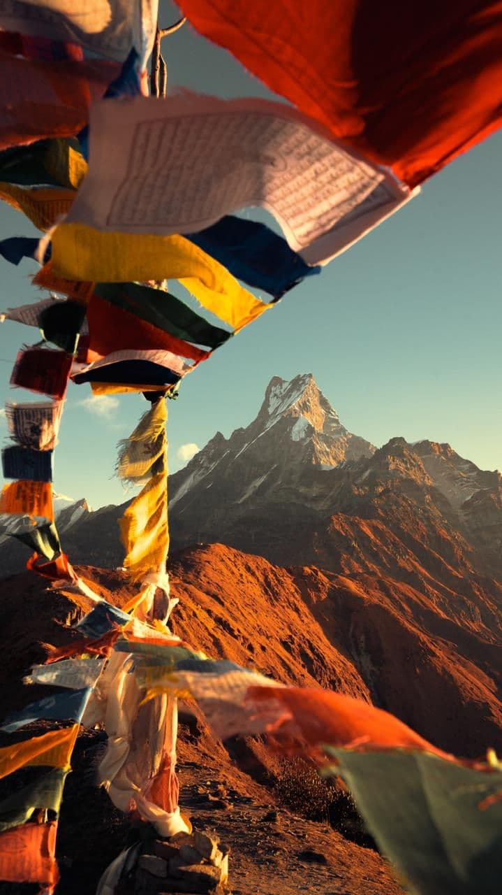 Prayer flags framing a red-lit peak at sunrise